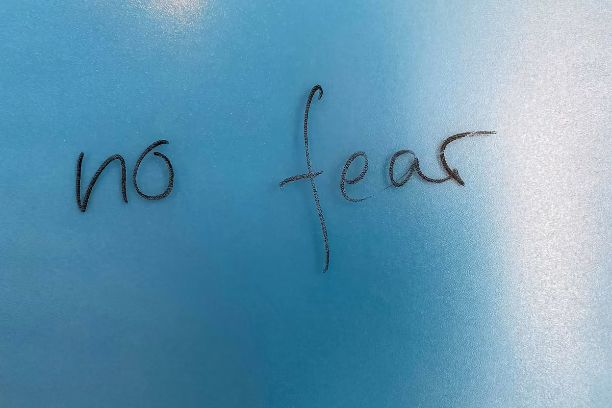 The phrase 'No Fear' written on a blue surface with a light gradient.