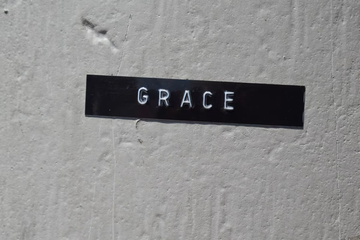 Black label with the word 'GRACE' printed in white embossed letters on a grey concrete wall.