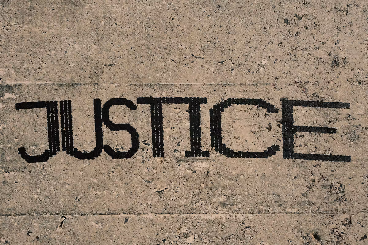 The word JUSTICE is stamped or painted in black on a gray concrete or stone surface.