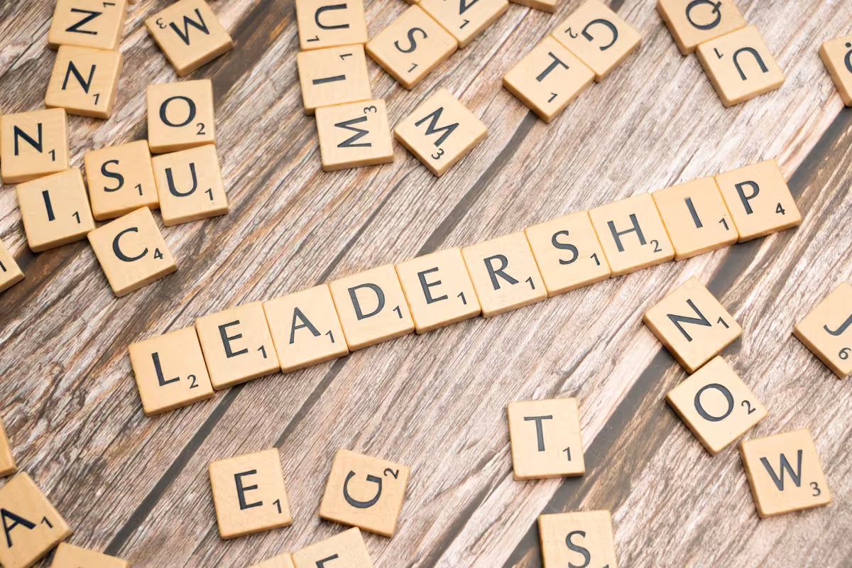 Scrabble tiles spelling the word leadership on a wooden surface.